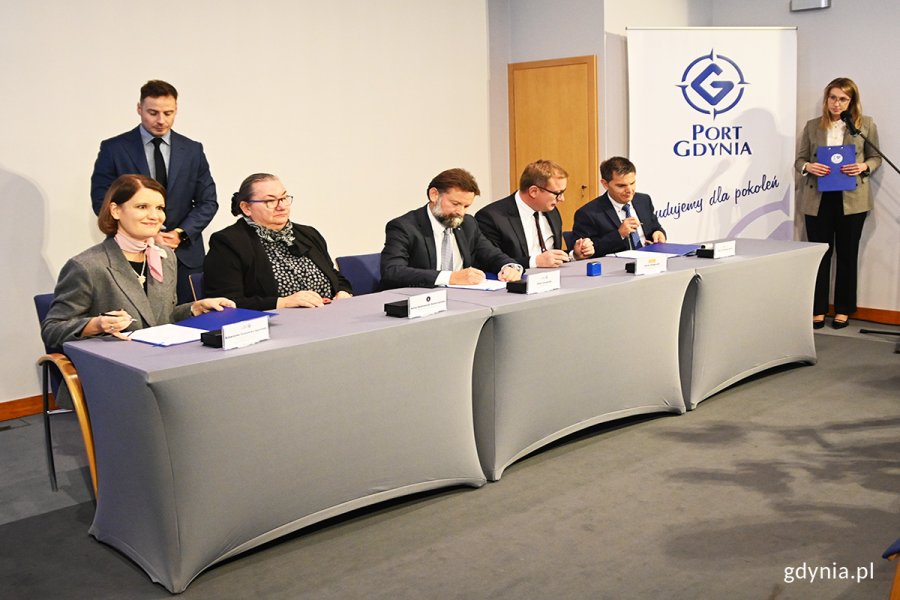 Ludzie za stołęm podpisują umowę