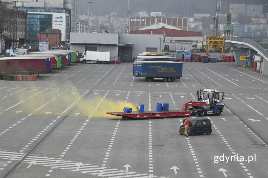 Pojazd transportowy i samochód osobowy na miejscu pozorowanego wypadku na pustym parkingu, widoczny dym imitujący chlor