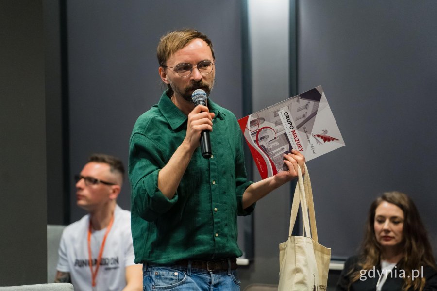 Mężczyzna z mikrofonem pokazuje książkę