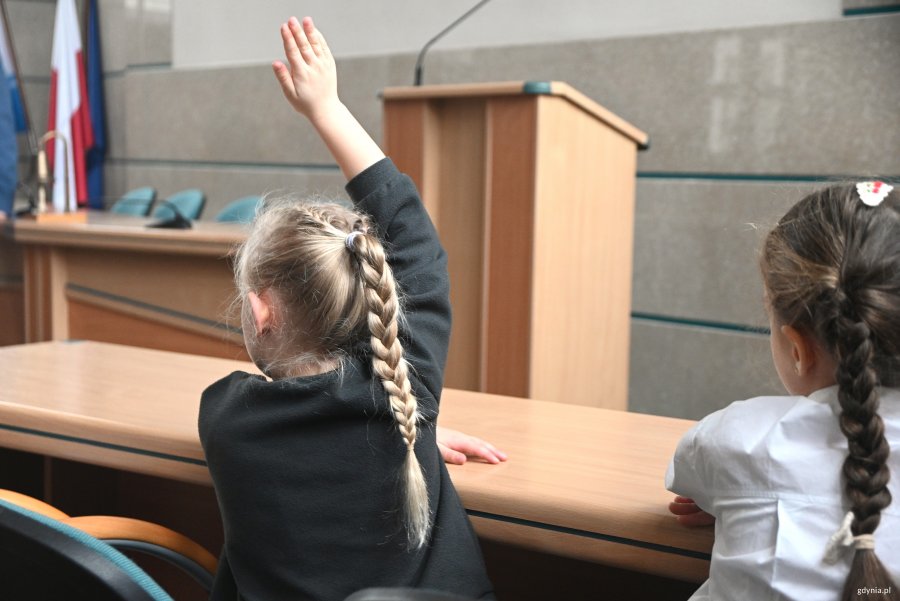 Dziwczynka z warkoczem trzyma rękę w górze