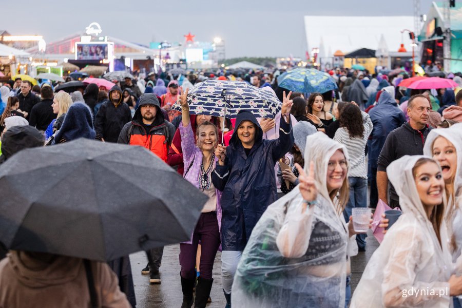 Uczestnicy Open'era spacerujący po miasteczku festiwalowym w pelerynach przeciwdeszczowych i z parasolami// fot. Karol Stańczak