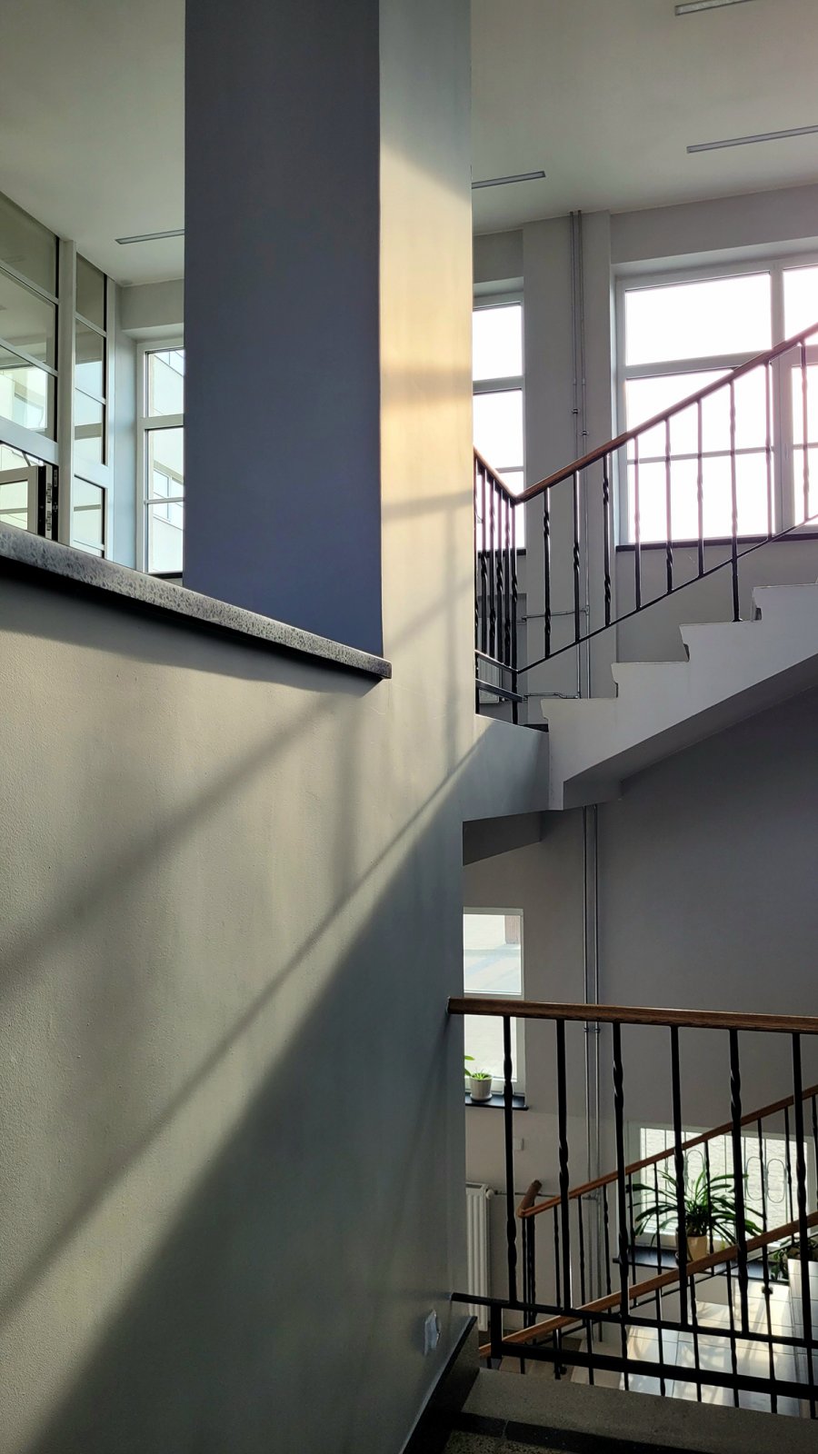 Klatka schodowa budynku z balustradami i oknami.