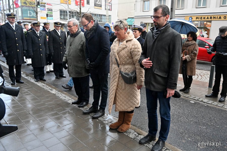 Grupa osób składa hołd pod pomnikiem.