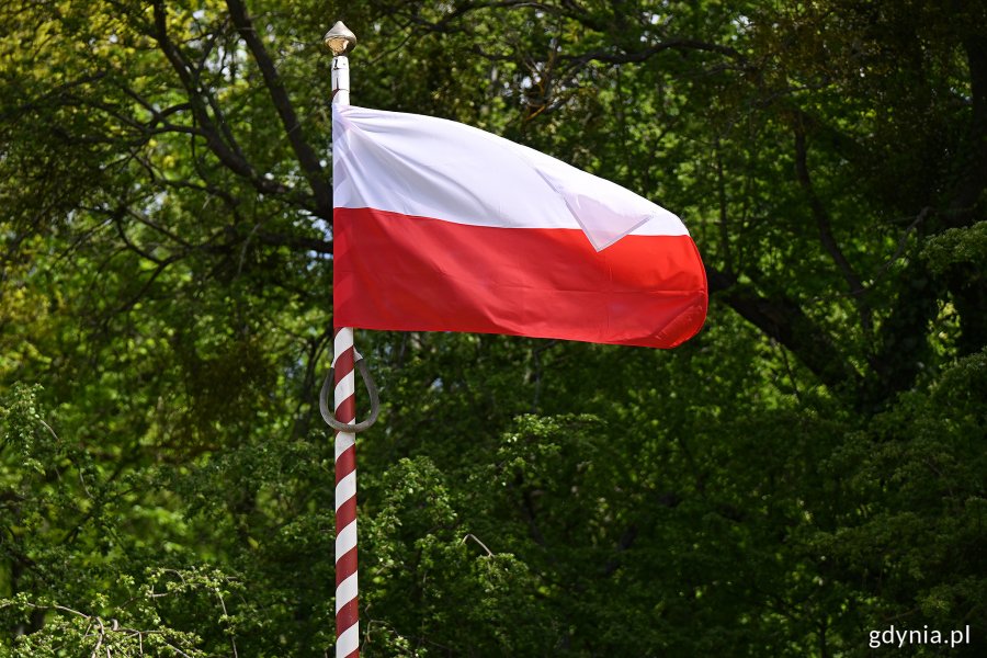 Biało-czerwona flaga powiewająca na wietrze podczas uroczystości z okazji Święta Narodowego Trzeciego Maja 