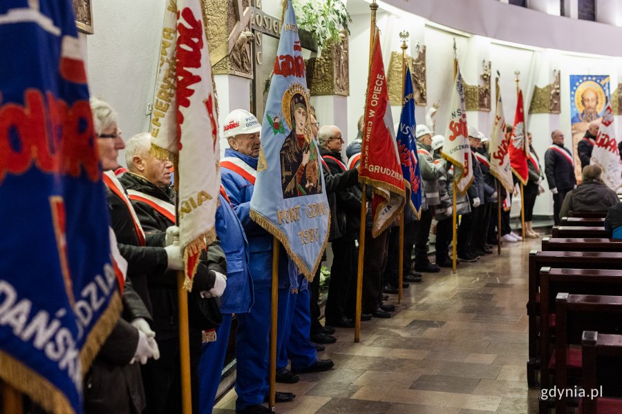 Ludzie w odświętnych strojach stoją w kościele