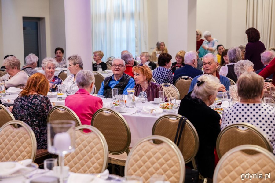 Grupa senior&oacute;w siedzi przy elegancko zastawionym stole