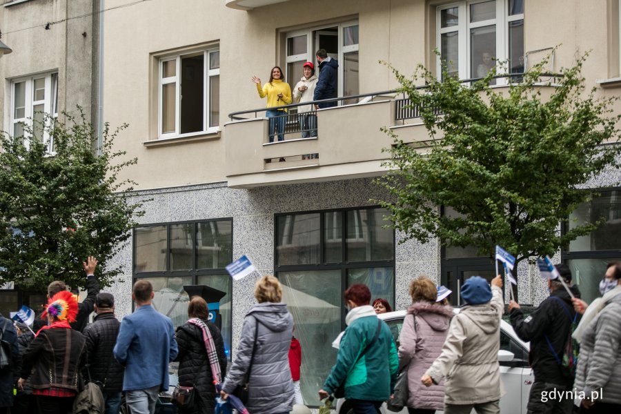 Wielobarwny Pomorski Przemarsz Seniorów ulicami Gdyni. Paradę obserwują z balkonu mieszkańcy. Fot. Karol Stańczak
