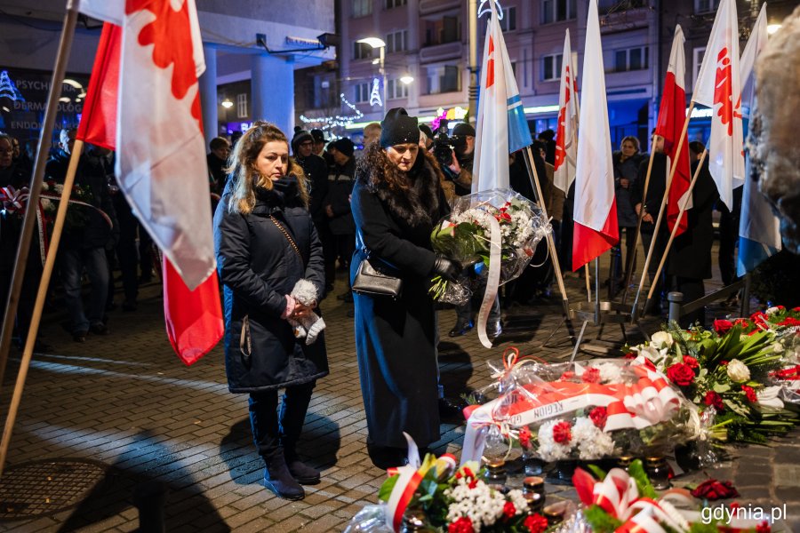 Dwie kobiety składające kwiaty przed pomnikiem
