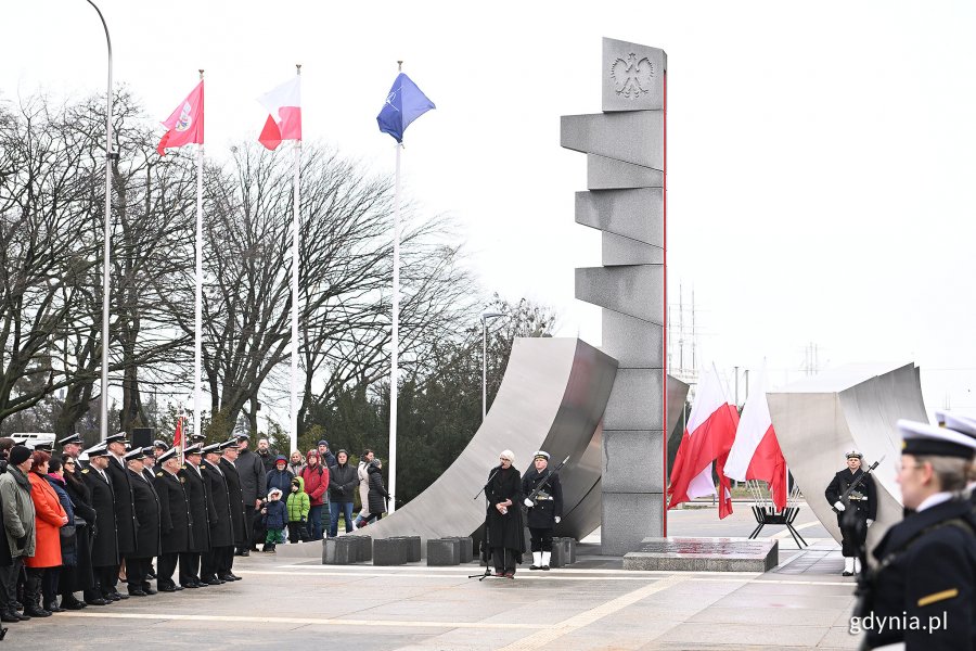 Joanna Zielińska - przewodnicząca Rady Miasta Gdyni przemawiająca podczas uroczystości z okazji 98. rocznicy nadania Gdyni praw miejskich, które odbyły się przed pomnikiem Polski Morskiej. Za nią posterunek honorowy przy pomniku. Po bokach uczestnicy uroczystości oraz kompania honorowa