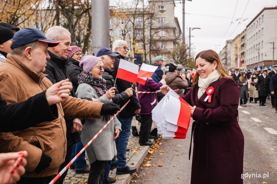 Prezydent Gdyni Aleksandra Kosiorek wręczająca biało-czerwone flagi (fot. Karol Stańczak)
