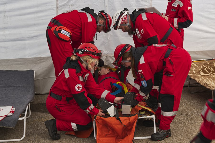 Na zdjęciu czterech ratowników pomaga poszkodowanej kobiecie na noszach.