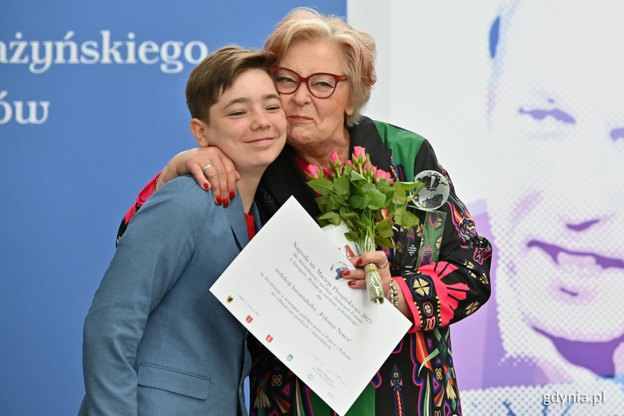 Teresa Sygnarek z kwiatami, statuetką i dyplomem. Obok niej stoi chłopiec z Białorusi