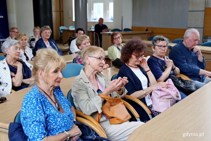 Seniorzy siedzą w ławach radnych miasta.