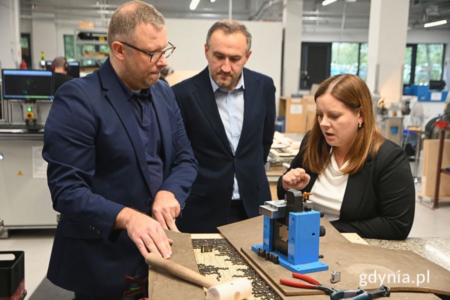 Grupa osób oglądająca maszyny używane do produkcji puzzli i gier