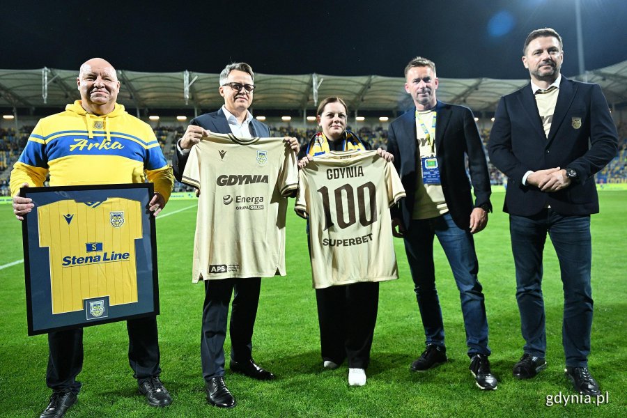 Wsp&oacute;lne zdjęcie i przekazanie okolicznościowych koszulek. Od lewej: Marek Kiersnowski, dyrektor zarządzający Stena Line Polska, Dariusz Wichniarek, dyrektor ds. rozwoju biznesu Advanced Protection Systems SA, Aleksandra Kosiorek, prezydent Gdyni, Marcin Gruchała, przewodniczący Rady Nadzorczej Arki Gdynia oraz Wojciech Pertkiewicz, prezes zarządu Arki Gdynia 