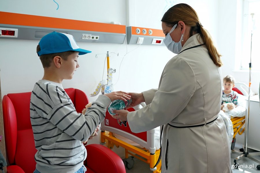 Prezydent Aleksandra Kosiorek wręcza pluszowego misia i kubek jednemu z małych pacjentów Oddziału Pediatrycznego Szpitala św. Wincentego a Paulo w Gdyni i jego bratu 