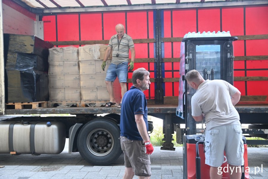 Trzech mężczyzn ładuje do ciężarówki paczki z pomocą dla Chersonia