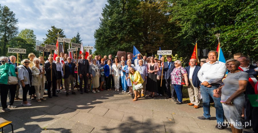 Grupa ludzi z tabliczkami pod pomnikiem