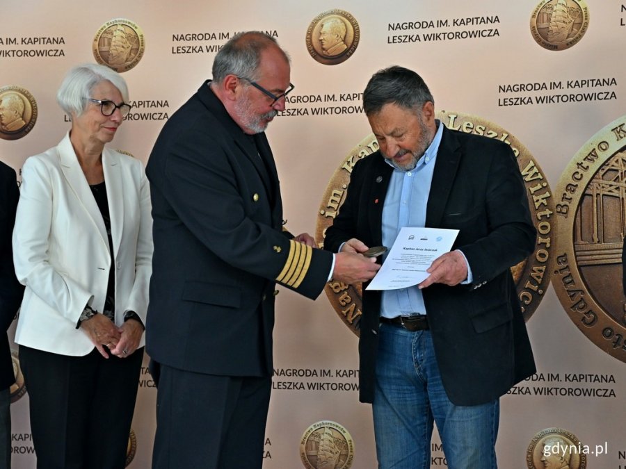 kpt. Jerzy Jaszczuk - laureat Nagrody im. Kapitana Leszka Wiktorowicza odbiera nagrodę z rąk kpt. ż. w. Mariusza Wiktorowicza - syna patrona nagrody. Obok stoi Joanna Zielińska - członkini kapituły i radna Gdyni