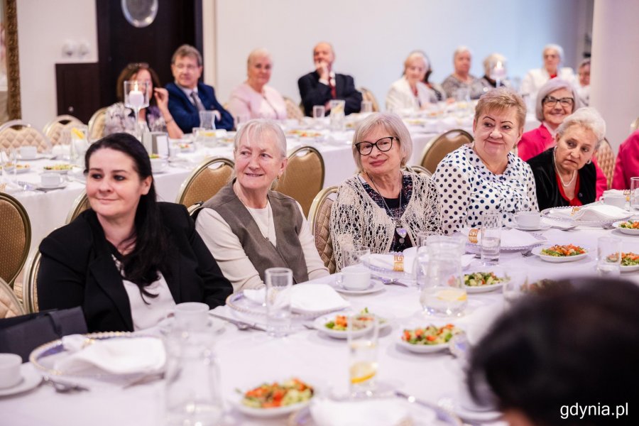 Grupa senior&oacute;w siedzi przy elegancko zastawionym stole