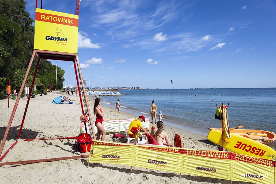 Grupa ratowników na plaży obok wieżyczki.