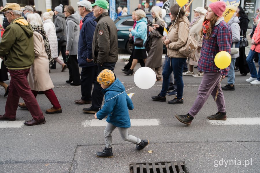 W procesji ulicą Świętojańską idą dorośli i dzieci z balonikami