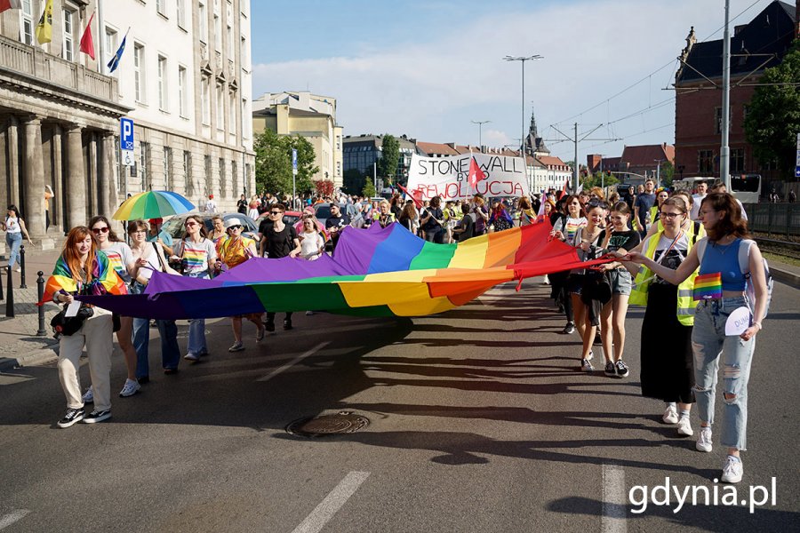 Grupa osób z tęczowymi flagami i transparentami