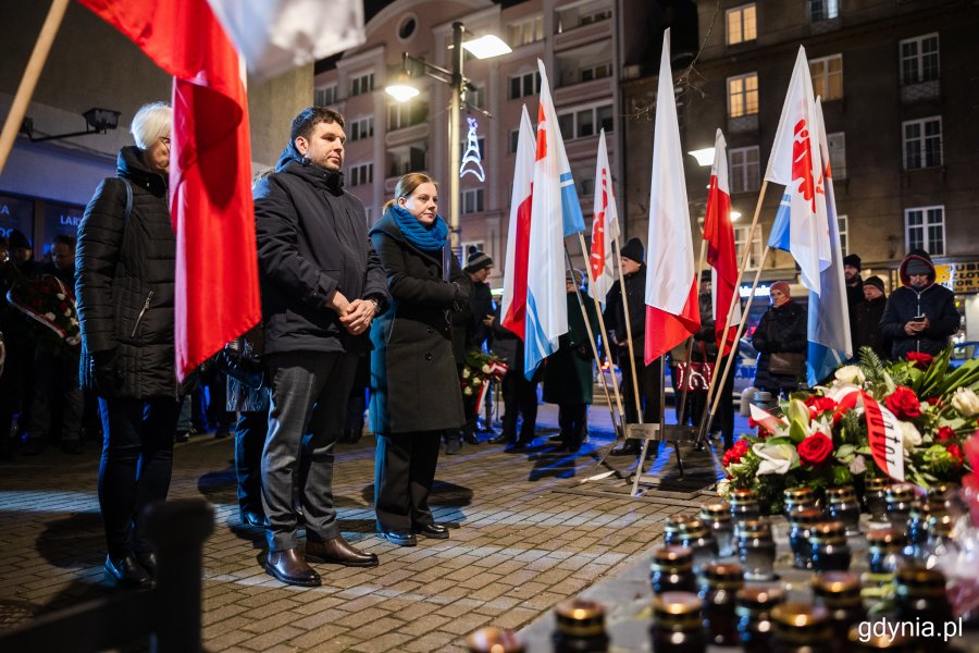 Grupa osób stojących przed pomnikiem