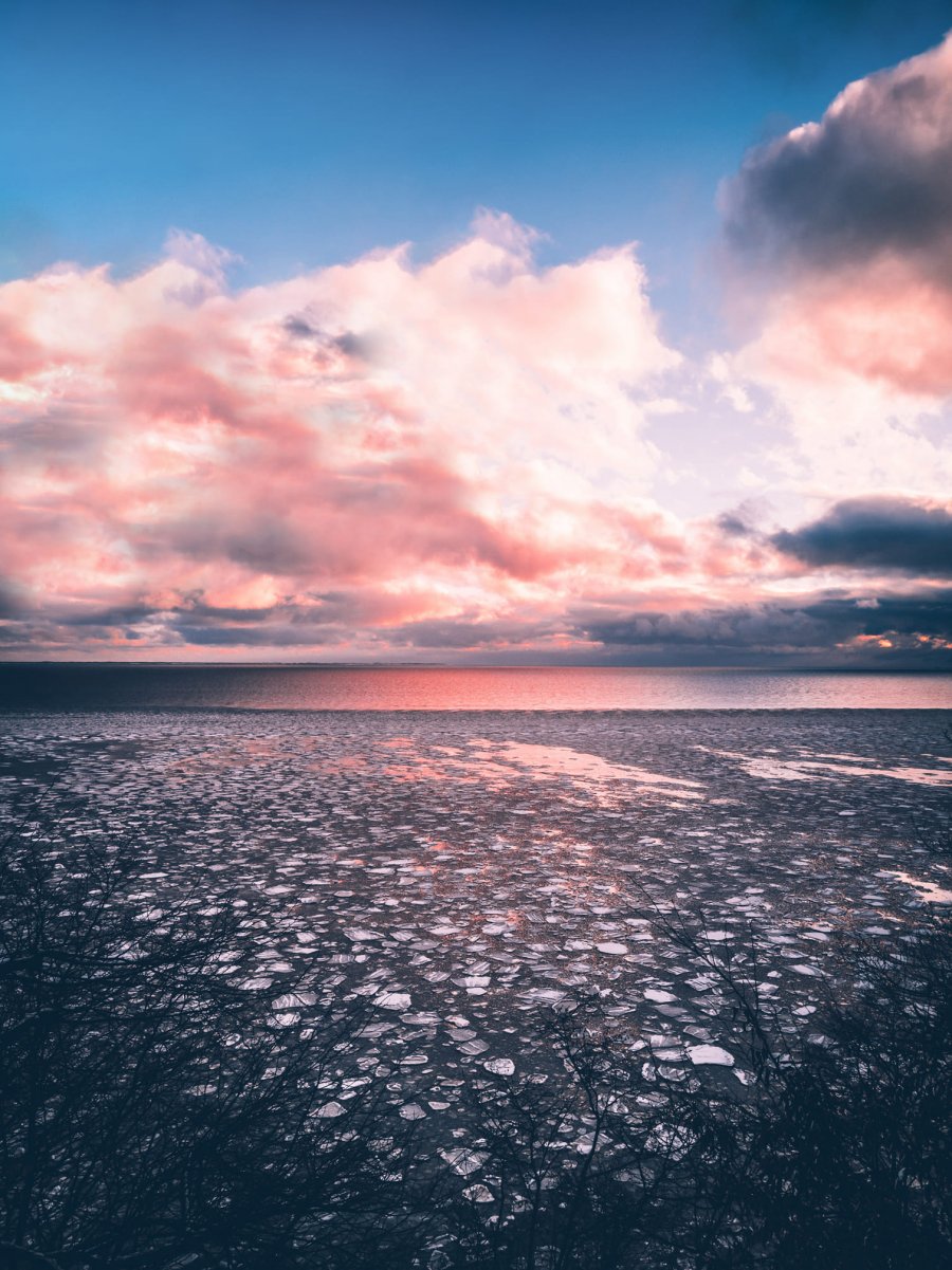 Osada Rybacka, widok na morze pokryte lodem, w tle różowe, zachmurzone niebo, fot. Maciej Gaweł