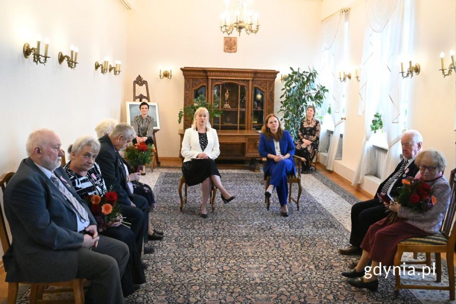 Seniorzy siedzący na krzesłach w eleganckiej sali