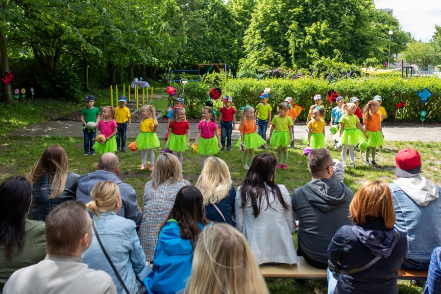 Dzieci podczas występu na terenie ogrodu na pierwszym planie publiczność 
