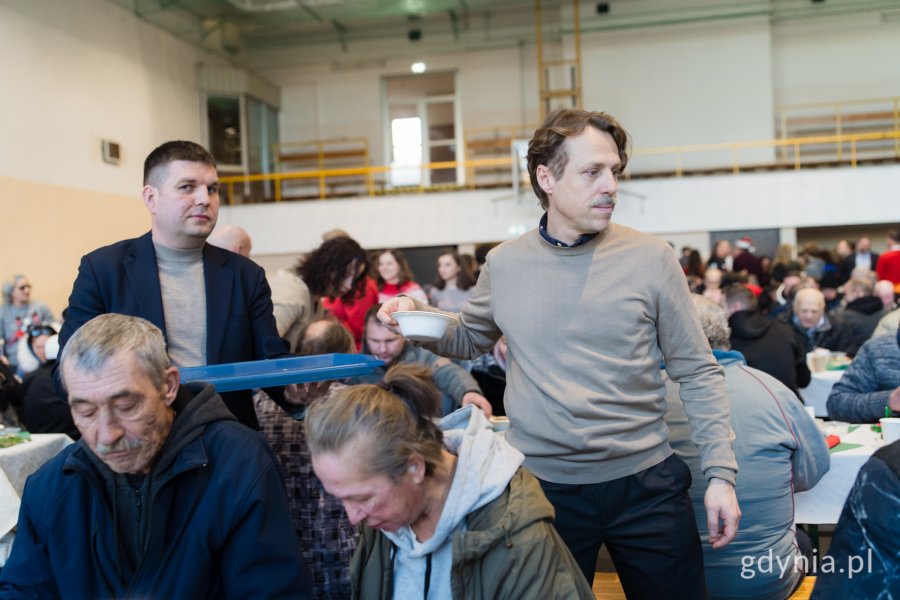 Wiceprezydent Maciej Zielonka i radny miasta Łukasz Piesiewicz roznoszący świąteczne potrawy gościom wigilii dla samotnych i potrzebujących