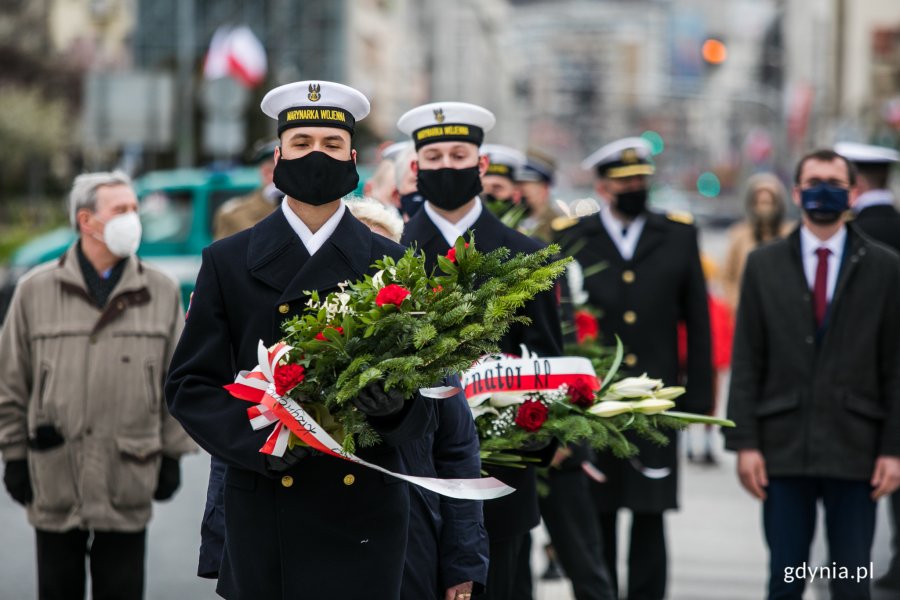 Marynarze ustawieni w rzędzie z wieńcami i wiązankami kwiatów // fot. Karol Stańczak