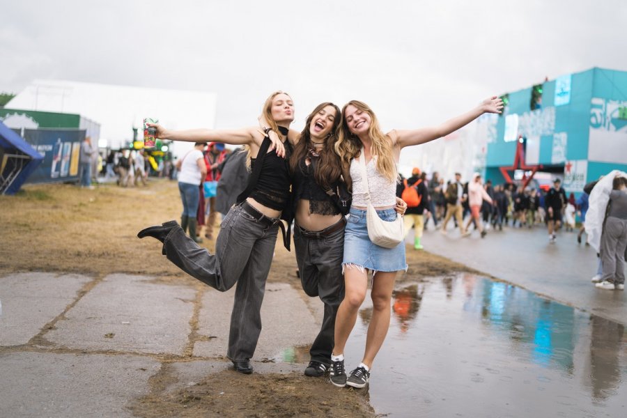 Trzy uczestniczki Open'era stoją w strugach deszczu w miasteczku festiwalowym // fot. Magda Zaklika