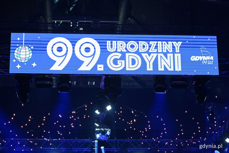 Hala Polsat Plus Arena Gdynia, niebieskie światło, wyświetlacz led z napisem "99. urodziny Gdyni" i logotyp miasta