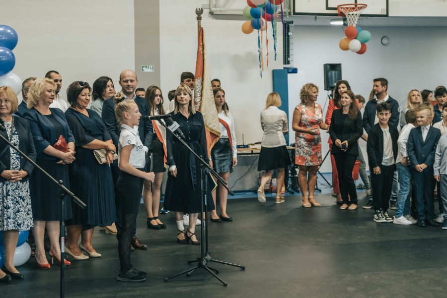 Młoda dziewczyna przy mikrofonie w tle przedstawiciele władz