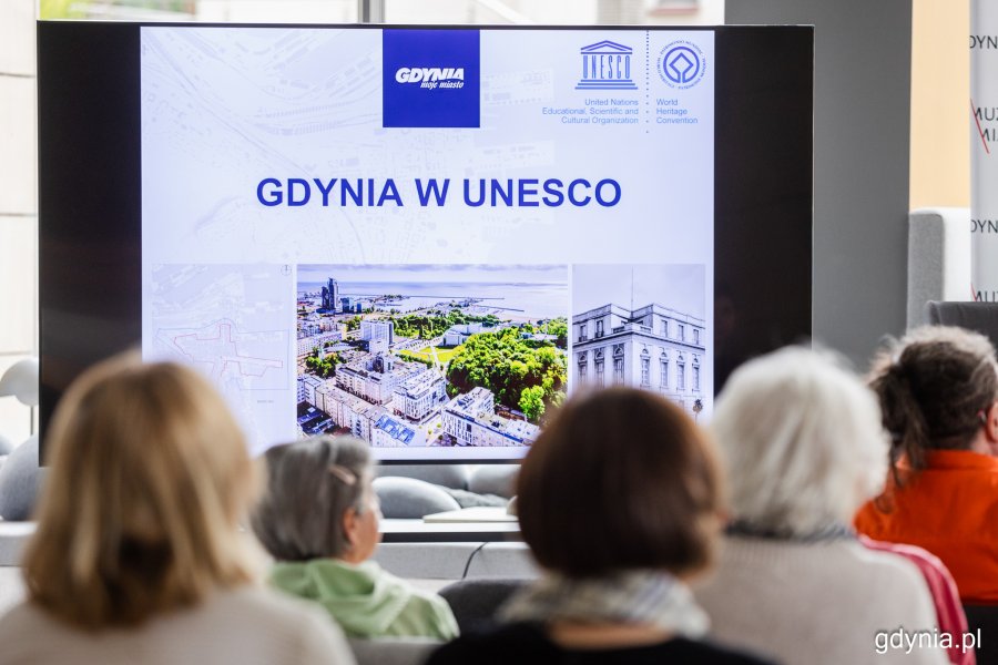 Plansza ze zdjęciem i napisem „Gdynia w UNESCO” podczas spotkania „Wtorki z modernizmem” w Muzeum Miasta Gdyni 