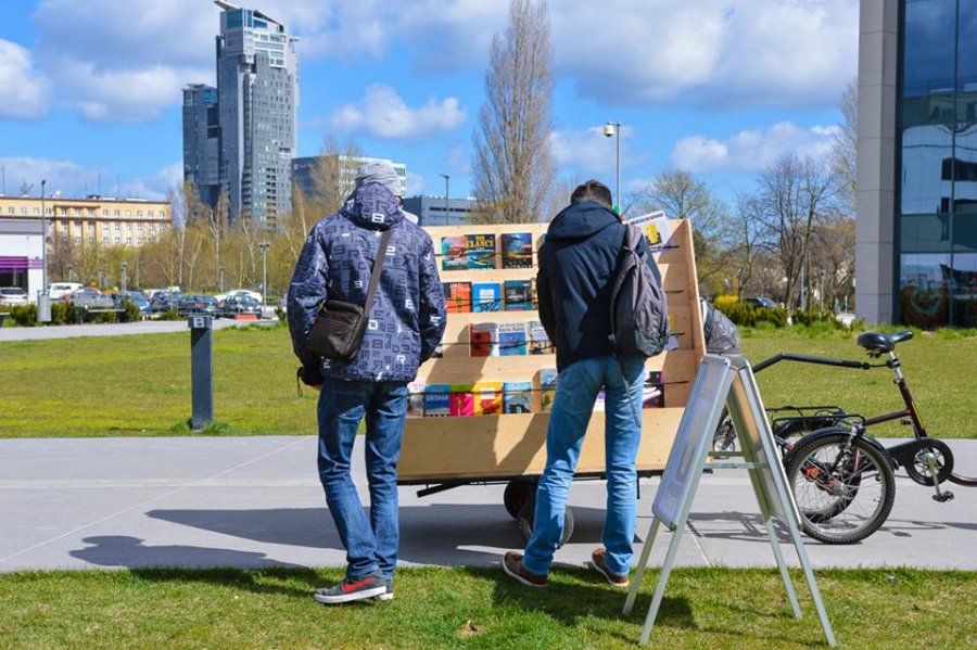 Dwie osoby przeglądają książki wystawione w punkcie bookcrossingowym