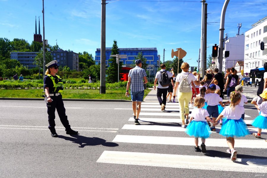 Policantka asekuruje przedszkolaki na przejściu dla pieszych