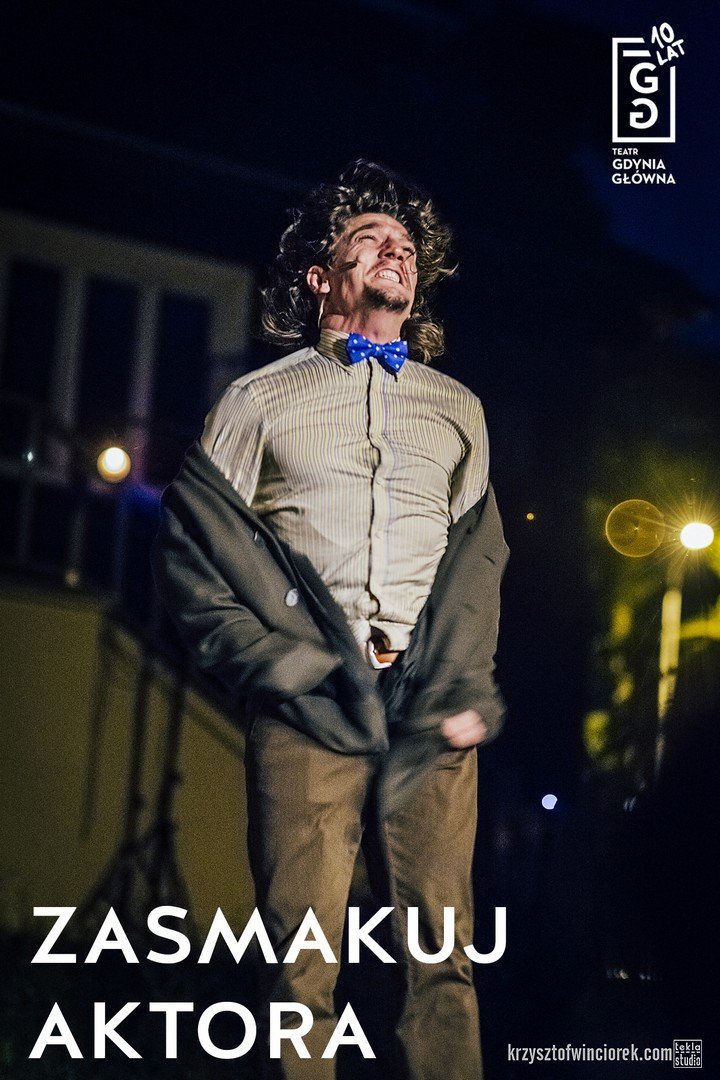 Grafika promująca wydarzenie Jubileusz 10-lecia Teatru Gdynia Główna. "Zasmakuj aktora". Mężczyzna zdejmujący marynarkę, z szarą koszulą i niebieską muszką. Ma grymas na twarzy. W tle scena teatralna. W prawym górnym rogu logo Teatru Gdynia Główna.