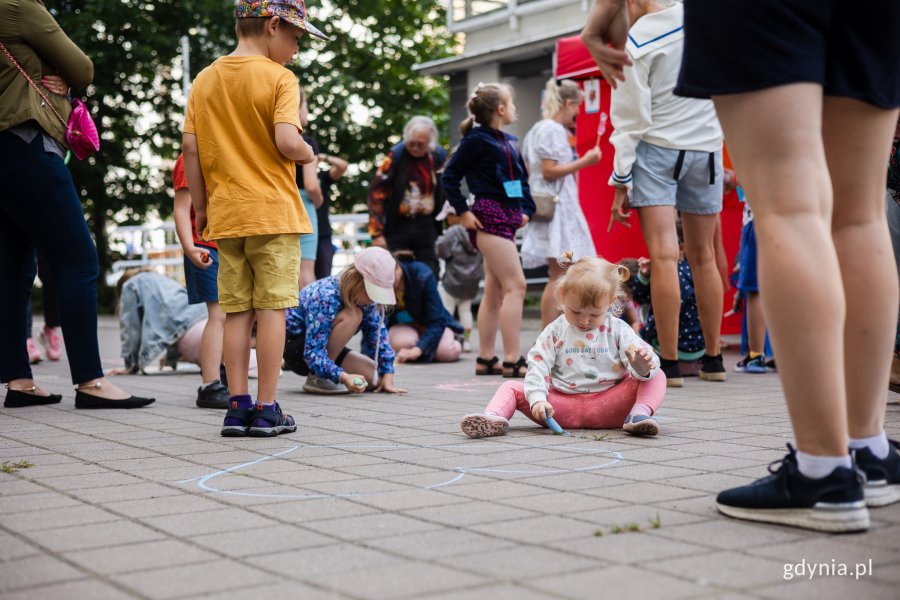 Dzieci rysują kredą na chodniku.