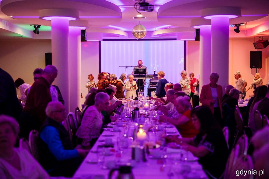 Grupa senior&oacute;w siedzi przy elegancko zastawionym stole