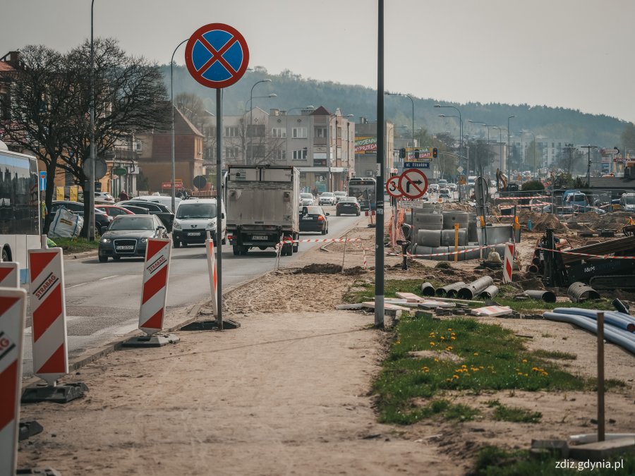 trwające roboty drogowe, widoczne elementy infrastruktury, oznakowanie, ruch uliczny