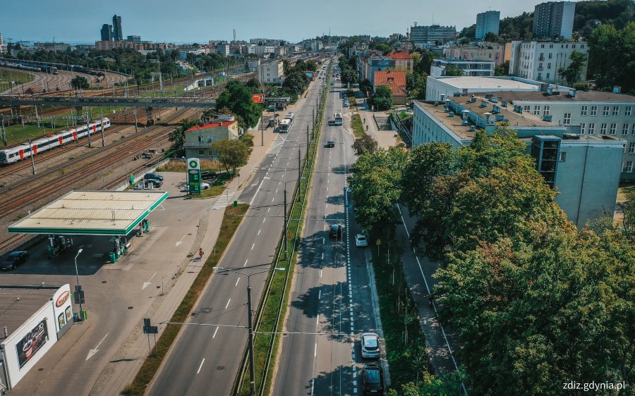 widok z góry na ulicę, w tle ruch uliczny, budynki i zieleń, widok z góry na miasto