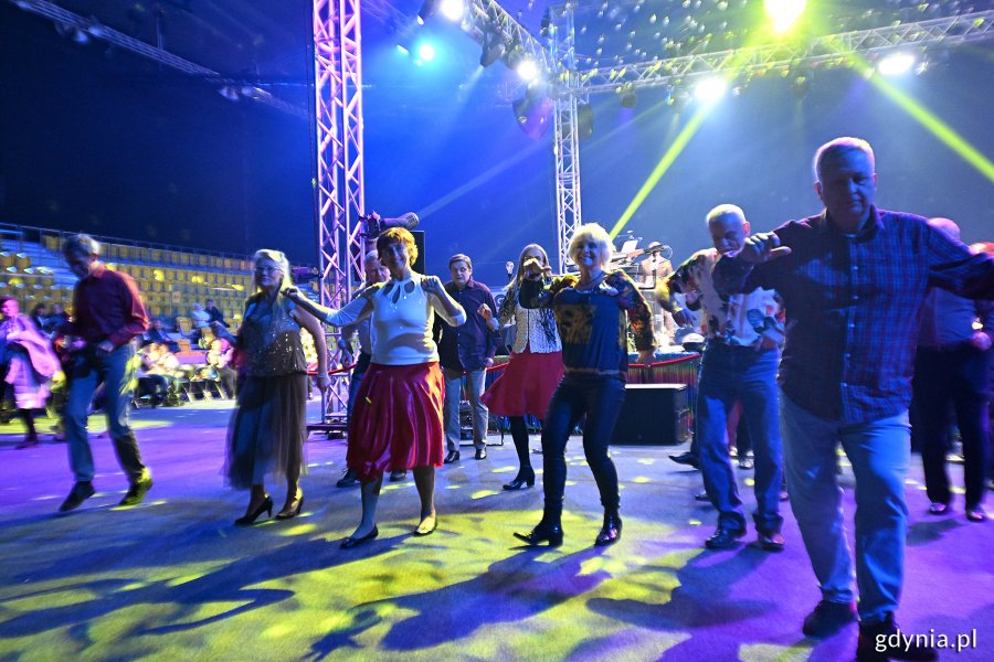 Hala Polsat Plus Arena Gdynia, scena, niebieskie światło, kolorowe oświetlenie, grupa seniorów tańczy