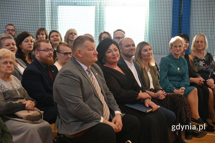 Kobiety i mężczyźni siedzący na krzesłach w szkolnej hali gimnastycznej
