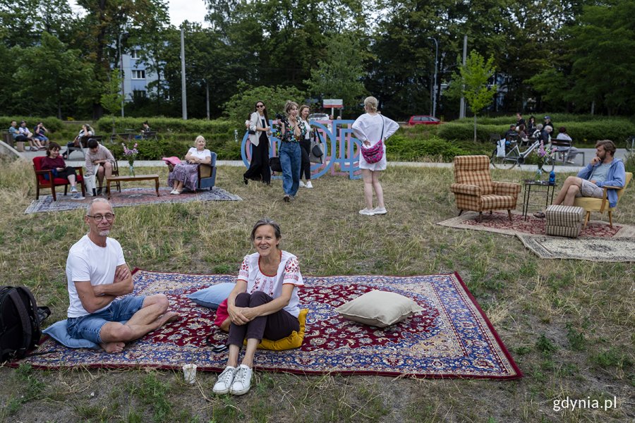 Ludzie siedzą na dywanie na trawie.