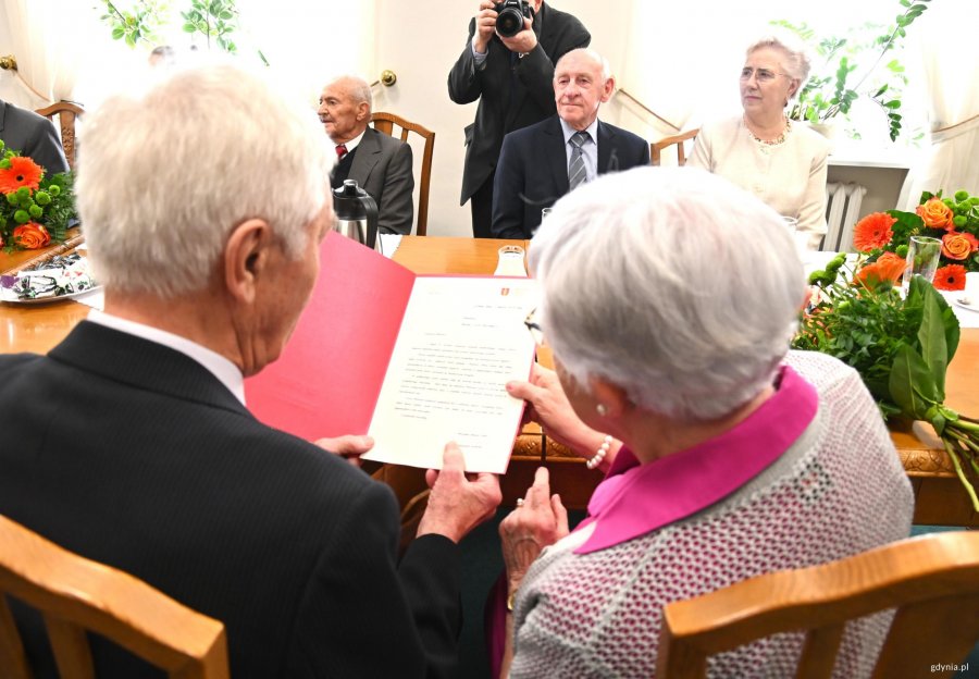 Starsi państwo z siwymi włosami wsp&oacute;lnie czytają list