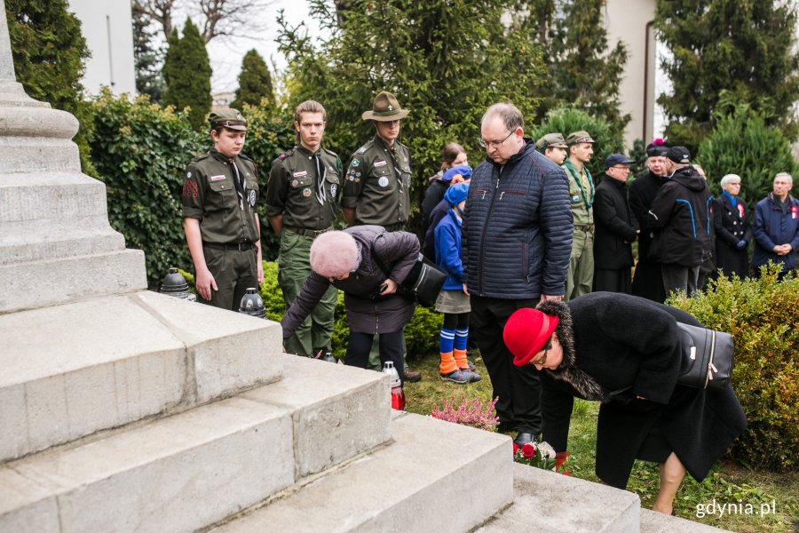 Radny Gdyni Paweł Stolarczyk złożył kwiaty przed pomnikiem Ofiar I Wojny Światowej. Obok niego dwie pochylone kobiety. Z tyłu inni uczestnicy uroczystości // fot. Karol Stańczak