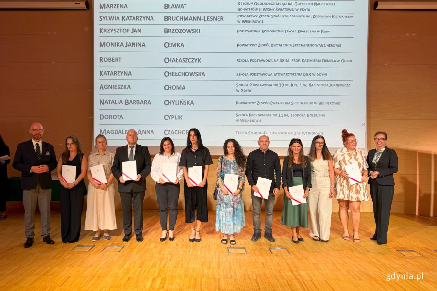 Osoby na scenie pozujące do zdjęcia po wręczeniu nominacji